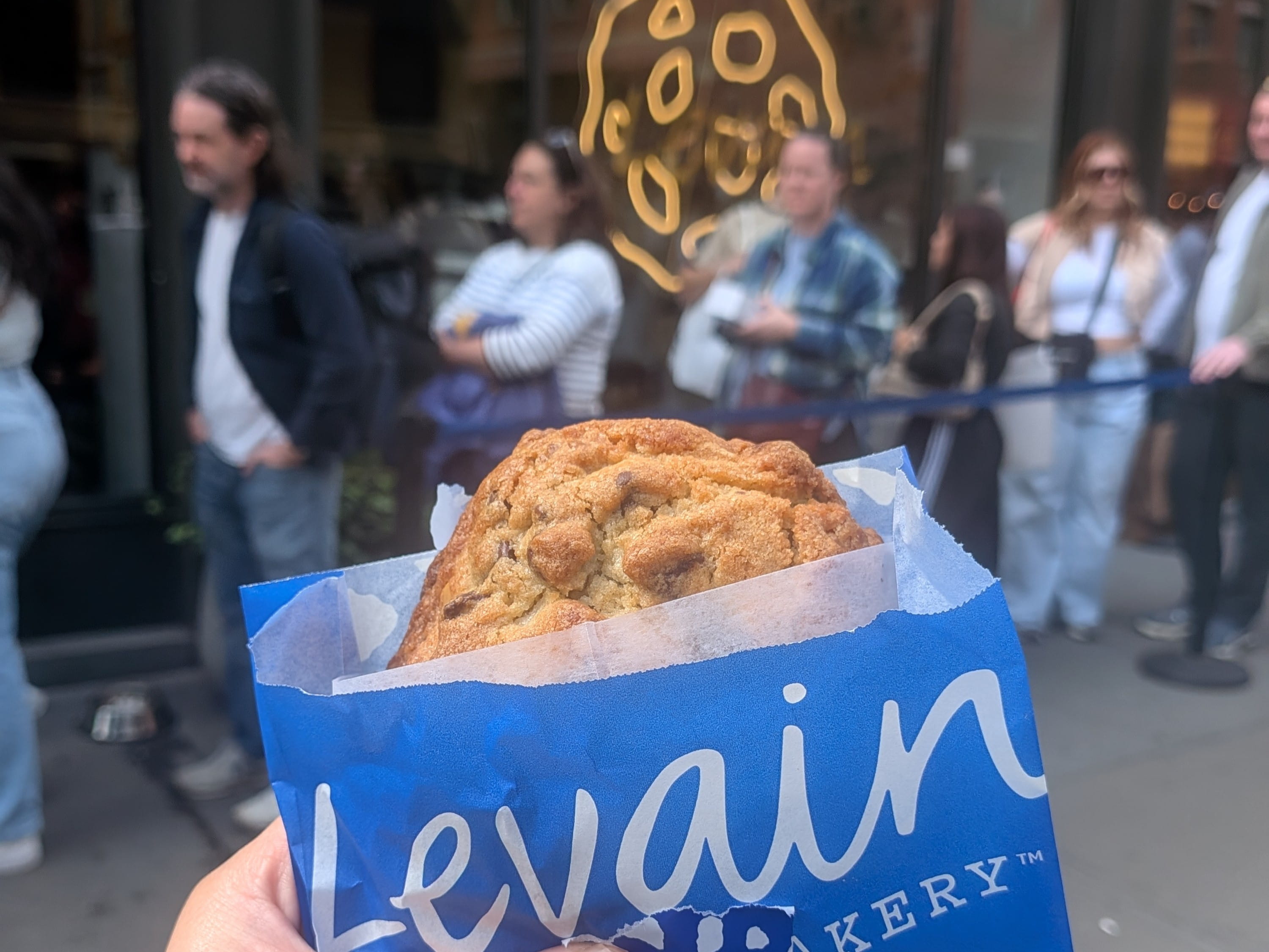 Levain Bakery cookie held up outside the bakery